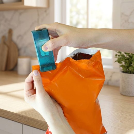 Handheld teal bag sealer being used to create an airtight seal on an orange snack bag.